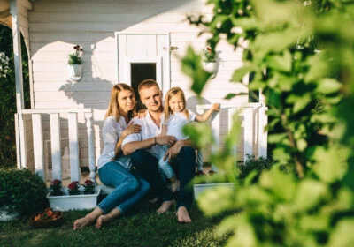 Smiling family with little child sitting together on porch of little country house